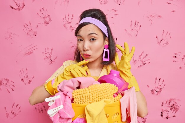 Zelfverzekerde huisvrouw poseert over roze muur met handafdrukken