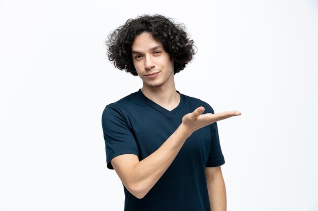 Zelfverzekerde jonge knappe man kijkend naar camera met lege hand geïsoleerd op een witte achtergrond