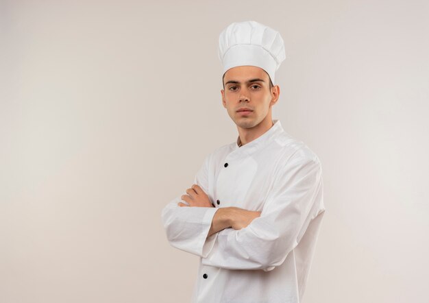 zelfverzekerde jonge mannelijke kok die chef-kok uniforme kruising handen op geïsoleerde witte muur met kopie ruimte draagt