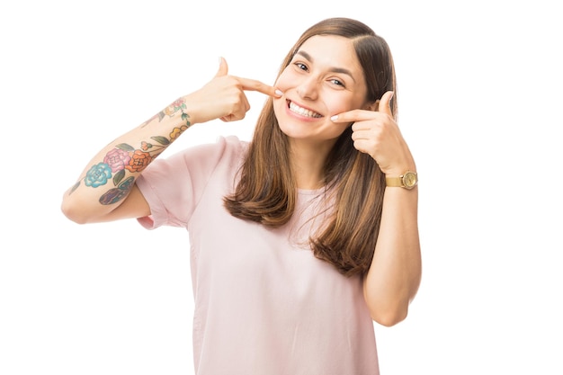 Zelfverzekerde jonge vrouw die haar perfecte rechte witte tanden toont tegen een witte achtergrond