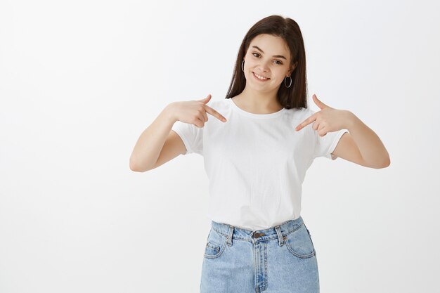 zelfverzekerde jonge vrouw poseren tegen witte muur