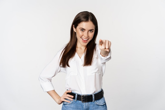 Zelfverzekerde jonge zakelijke vrouw die met de vingers naar je camera wijst en uitnodigt om stan...