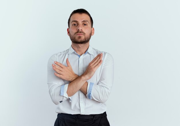 Zelfverzekerde knappe man kruist handen gebaren geen teken geïsoleerd op een witte muur