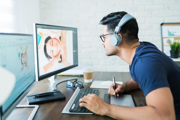 Zelfverzekerde mannelijke fotograaf die foto's retoucheert met grafisch tablet aan bureau