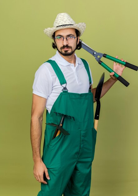 Zelfverzekerde tuinman met een optische bril die tuinhoeden draagt met tuingereedschap