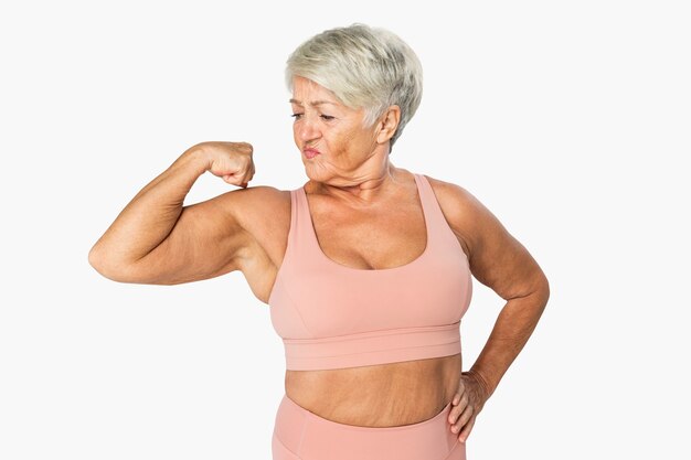 Zelfverzekerde volwassen vrouw in sportkleding die haar spier poseert