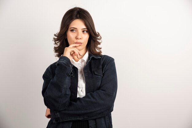 Zelfverzekerde vrouw in denim jasje staande op wit.