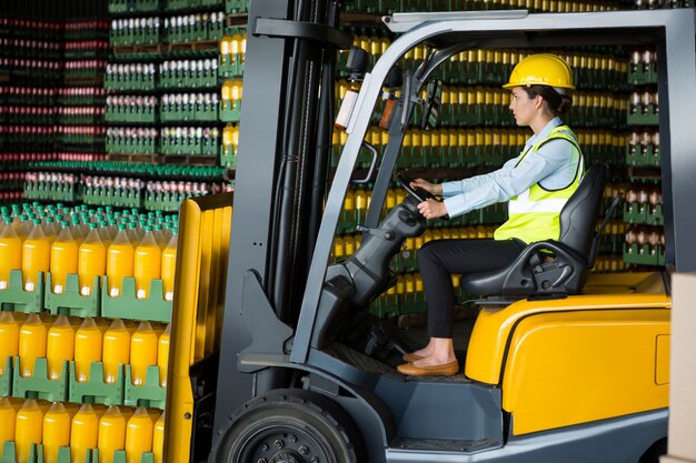 Zelfverzekerde vrouwelijke werknemer heftruck rijden in magazijn