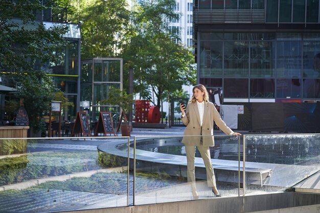 Zelfverzekerde zakenvrouw in beige pak die in power pose staat in het stadscentrum