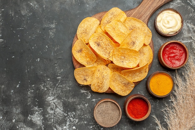 Zet aardappelchips met verschillende kruidenmayonaise en ketchup op grijs tafelmateriaal