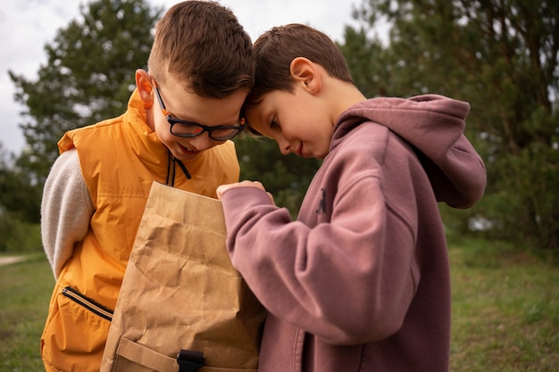 Gratis foto zicht op kleine jongens met rugzakken die buiten tijd doorbrengen in de natuur