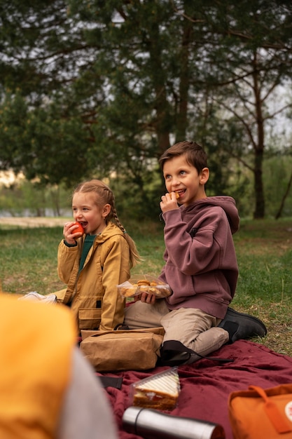 Gratis foto zicht op kleine kinderen met rugzakken die buiten tijd doorbrengen in de natuur