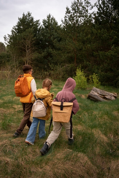 Gratis foto zicht op kleine kinderen met rugzakken die buiten tijd doorbrengen in de natuur