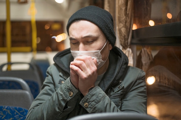 Gratis foto zieke man die in de bus hoest terwijl hij een medisch masker draagt