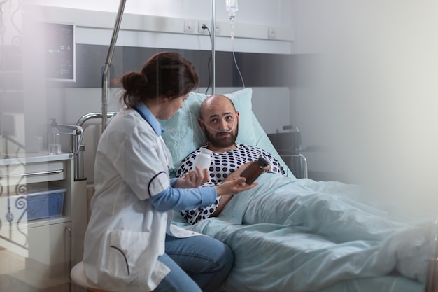 Zieke man patiënt met nasale zuurstofbuis rust in bed tijdens medisch onderzoek in ziekenhuisafdeling s...