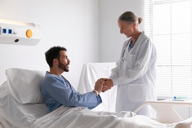 Zieke mannelijke patiënt in bed in gesprek met een verpleegster