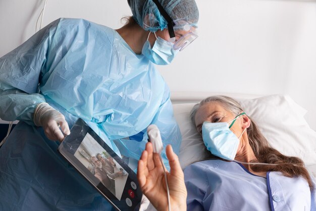 Zieke vrouwelijke patiënt in bed in het ziekenhuis in gesprek met familie via een tablet