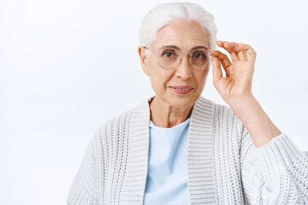 Gratis foto ziektekostenverzekering en pensioen concept vrolijke elegante oude dame in gezellige outfit grijs gekamd haar vaststelling van presctiption bril nieuwe brillen kiezen voor beter zicht bij opticiens glimlachend tevreden