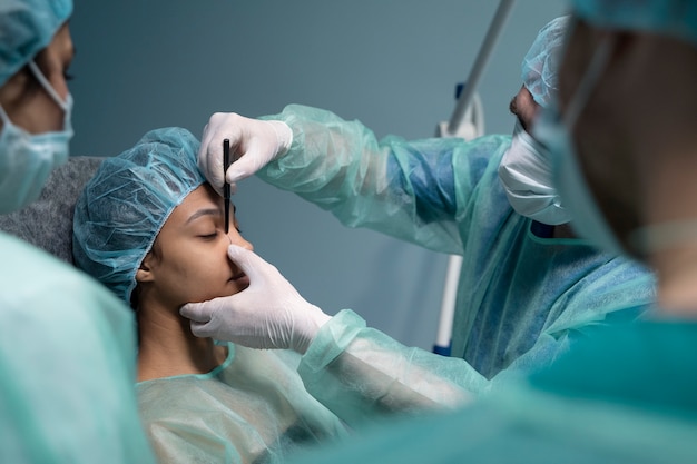 Zijaanzicht arts die patiënt controleert vóór neuscorrectie