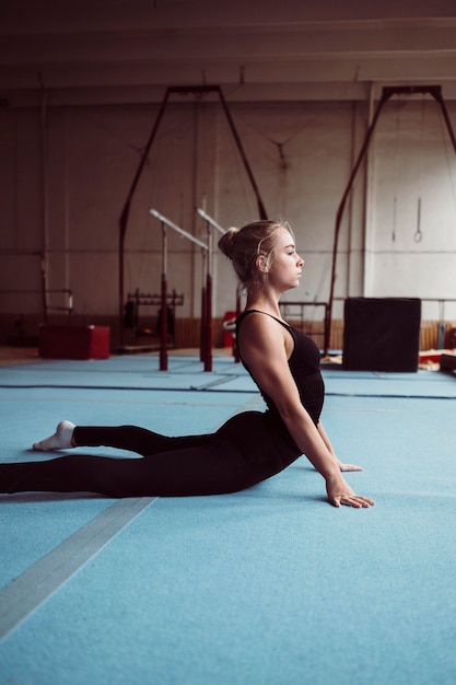 Zijaanzicht blonde vrouw training voor olympische gymnastiek