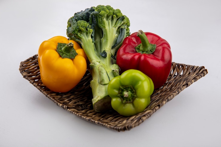 Gratis Foto zijaanzicht broccoli met gekleurde paprika op een stand op een witte achtergrond