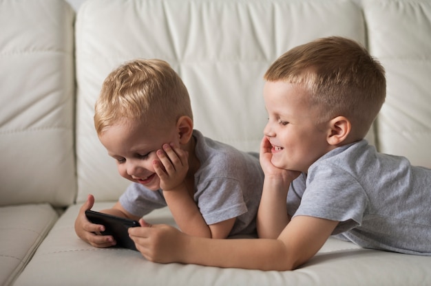 Zijaanzicht broers spelen op smartphone Gratis Foto