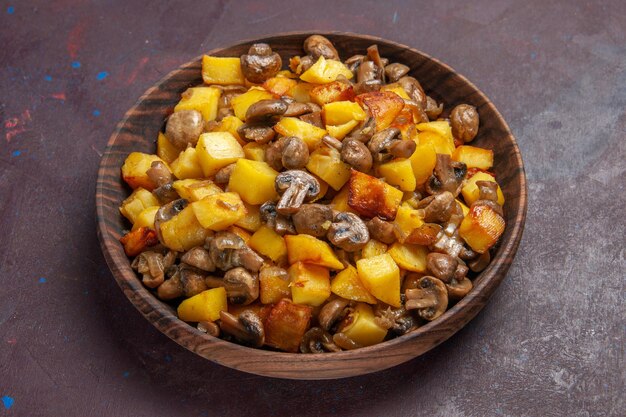 Zijaanzicht champignons met aardappelen in het midden van de donkere achtergrond zijn er gebakken aardappelen met champignons in een bruine kom op een paarse achtergrond