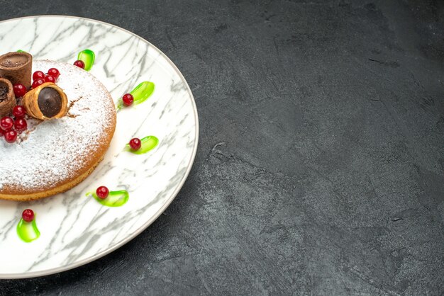 Zijaanzicht close-up een cake een cake met bessen poedersuiker wafels groene saus