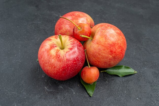 Zijaanzicht close-up fruit rood-gele appels en bessen met bladeren