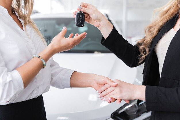 Zijaanzicht dat van vrouw autosleutels ontvangt