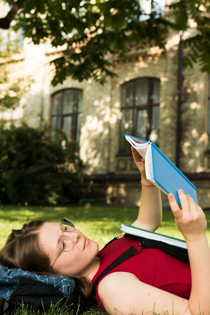 Zijaanzicht dichte omhooggaand van schoolmeisje die een boek lezen