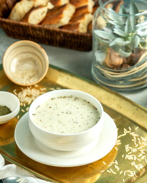 Zijaanzicht dovga-yoghurt soep traditionele Azerbeidzjaanse soep met rijst en gedroogde kruiden op een dienblad