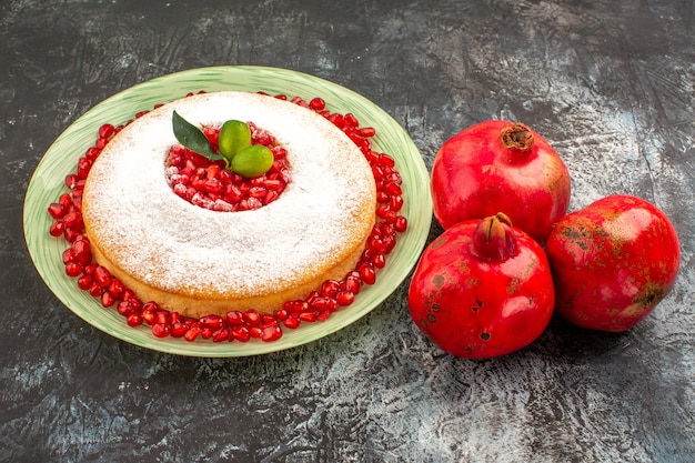 Gratis foto zijaanzicht een smakelijke cake een smakelijke cake met pitjes van granaatappel en drie granaatappels