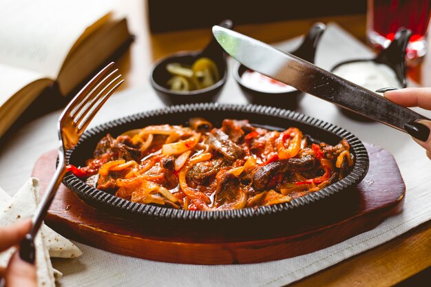 Zijaanzicht een vrouw eet vlees fajitos in een pan