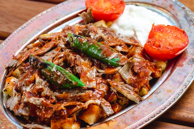 Zijaanzicht eilandbewoner doner met tomatensaus hete groene paprika gegrilde tomaat en yoghurt op een dienblad