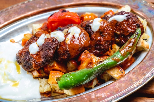 Zijaanzicht eilandbewoner kebab gegrilde vleeskoteletten met tomaten hete groene peper tomatensaus en yoghurt op een brood