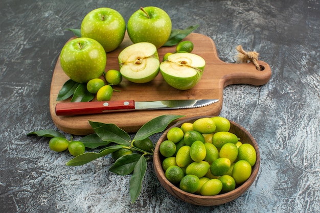 Zijaanzicht fruit appels met bladeren mes op de snijplank kom met citrusvruchten