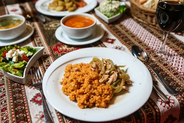 Zijaanzicht gebraden kip met uien bulgur en groente salade met soep op tafel