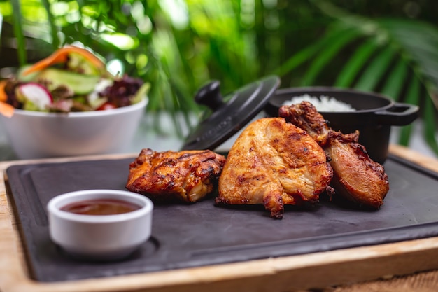 Zijaanzicht gegrilde kipfilet met saus en rijst garnituur op een dienblad