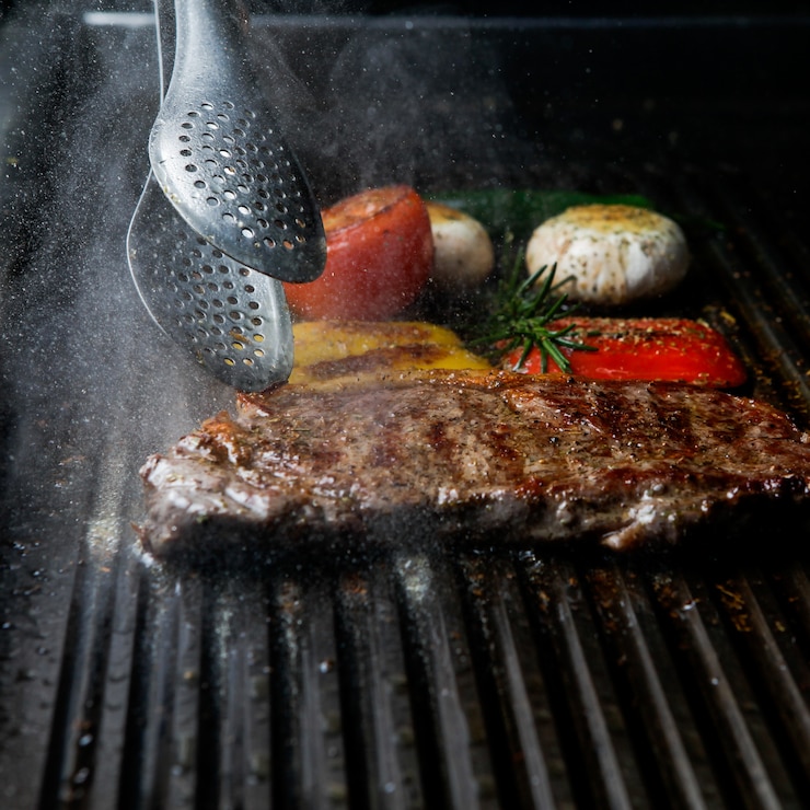 Gratis Foto zijaanzicht gegrilde steak met rozemarijn en champignons en barbecue tang in barbecue