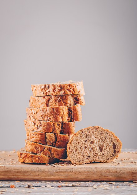 Zijaanzicht gesneden brood in snijplank op houten tafel en grijze oppervlak