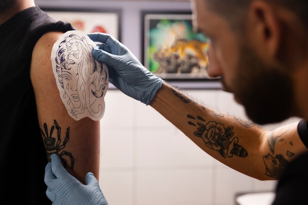 Zijaanzicht getalenteerde tattoo-artiest doet zijn werk