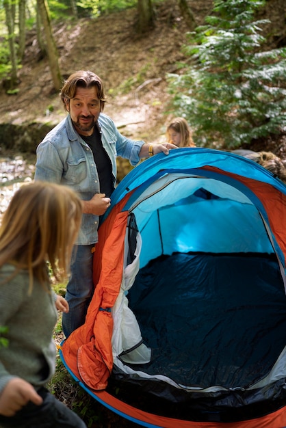 Zijaanzicht gezin met tent in de natuur