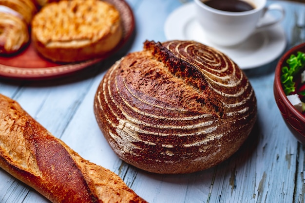 Gratis foto zijaanzicht gist gratis brood met stokbrood brood en kopje koffie op tafel