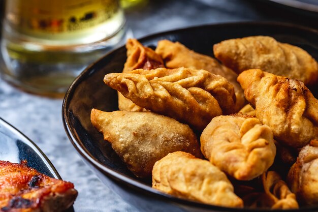 Zijaanzicht gurza gebakken lams dumplings met ui zout en peper op een plaat