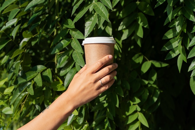 Gratis foto zijaanzicht hand met koffiekopje buitenshuis