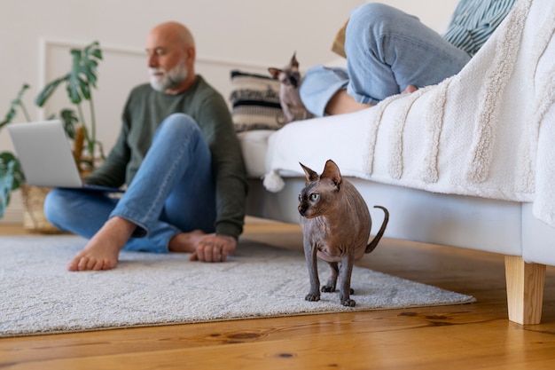 Gratis foto zijaanzicht hoger paar met kat thuis