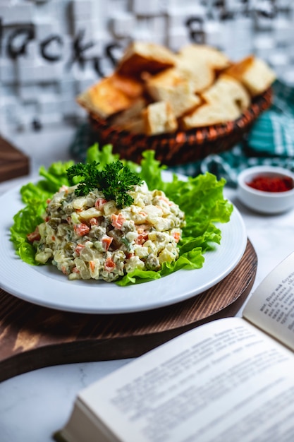 Zijaanzicht hoofdsalade op sla met een mand brood