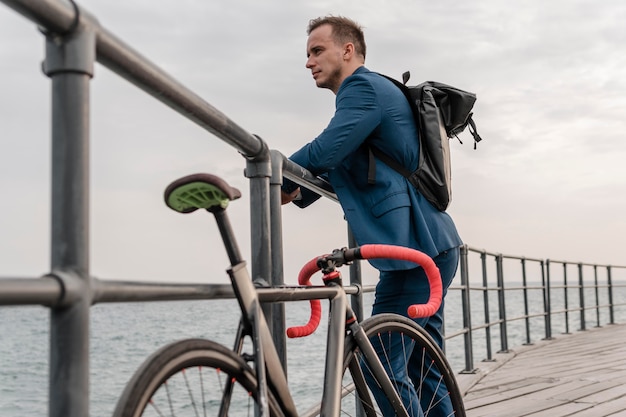 Gratis foto zijaanzicht jonge man die naast zijn fiets