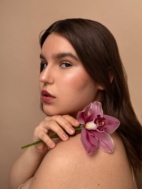 Zijaanzicht jonge vrouw poseren met bloem